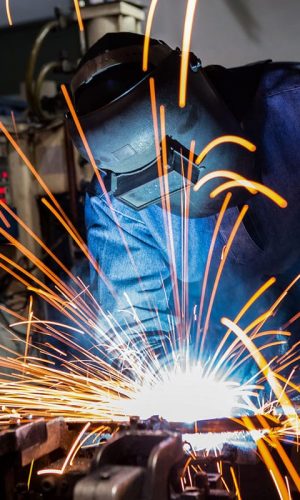 Industrial worker is welding car in factory